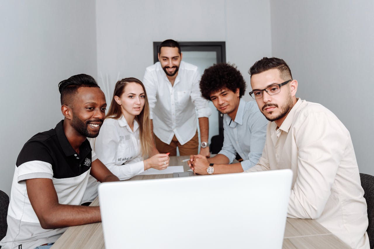 Mastering the First Impression: Your intriguing post title goes here A diverse group of professionals engaging in a collaborative meeting around a laptop in an office.