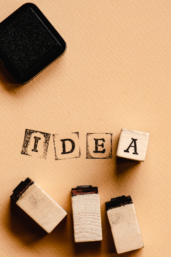 The Art of Drawing Readers In: Your attractive post title goes here Flat lay of 'IDEA' spelled with wooden stamps and ink pad, symbolizing creativity and innovation.